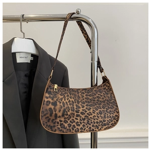 Detail of leopard print hobo bag with gold hardware on a minimalist clothes hanger