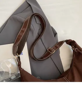 Detail showing the adjustable long shoulder strap with gold buckle on a brown tote bag