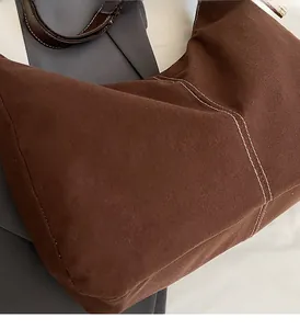 Detail of soft brown tote bag with white stitching on a grey blazer fabric