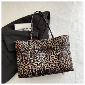 Flat lay of leopard print tote bag on white linen with a blazer and book