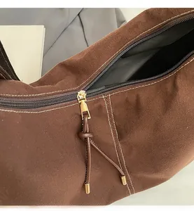 Detail of dark brown suede tote bag featuring a gold metal zipper and leather tassel pull