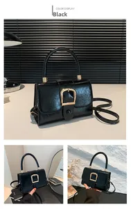 Detail of black glossy leather handbag featuring iconic golden horseshoe metal buckle