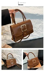 Detail view of brown faux leather handbag with textured finish and golden square buckle