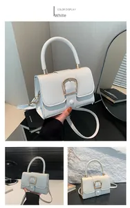 Detail of white faux leather crossbody bag with a large gold metal buckle and round handle