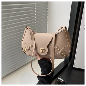 Detail of beige shoulder bag featuring a gold metal twist-lock and retro rivet accents