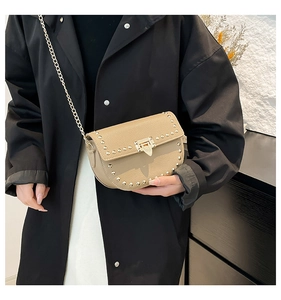 Detail of light brown rivet saddle bag with golden triangle clasp and chain strap