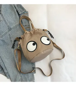 Detail of khaki nylon bucket bag with googly eyes motif and adjustable shoulder strap