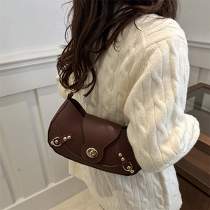 Retro dark brown crescent shoulder bag with gold hardware worn over white sweater