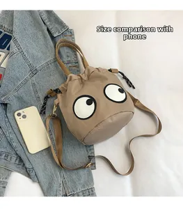 Detail view of khaki nylon bucket bag with eye patches compared to a smartphone