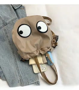 Detail view of khaki nylon bucket bag interior filled with daily essentials and cartoon eyes
