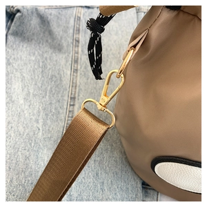 Detail of khaki nylon bucket bag with golden metal hook and drawstring closure