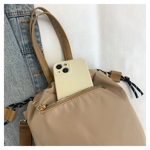 Detailed view of nylon tote zipper pocket showing capacity with a smartphone inside