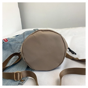 Macro view of the round bottom and durable nylon fabric of the khaki tote bucket bag