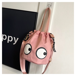 Detailed view of pink nylon bucket bag featuring cartoon eyes and adjustable woven strap