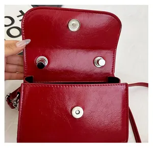 Gros plan du sac en cuir verni rouge montrant la boucle argentée et l'intérieur