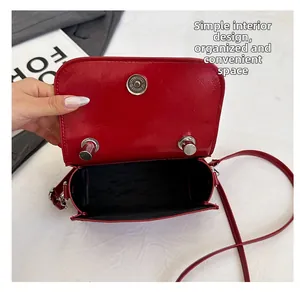 Détail d'un sac bandoulière en cuir verni rouge avec fermoir magnétique et intérieur