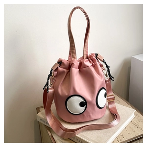 Close-up of pink nylon bucket bag with large cartoon eyes and gold drawstring hardware