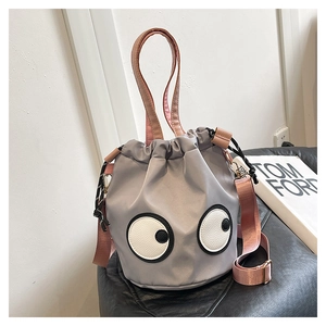 Detail of grey nylon bucket bag with googly eyes motif and pink shoulder strap
