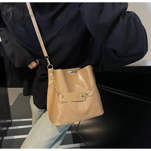 Close-up of brown leather bucket bag with gold chain and Fashion tag detail