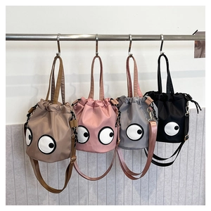 Detailed row of nylon bucket bags featuring quirky eye embroidery and adjustable straps
