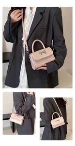 Detail showing the elegant silver bow buckle and matte pink texture on this crossbody bag