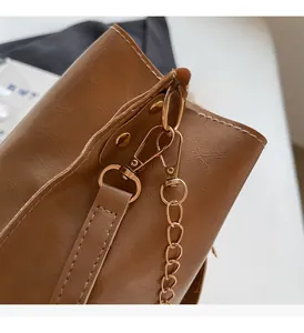 Detail shot of the brown leather bucket bag featuring shiny gold-tone metal hardware