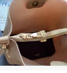 Detail of smooth golden zipper and magnetic closure on light brown leather bag