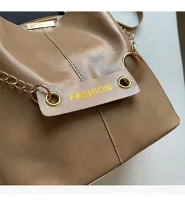 Close-up of brown PU leather bucket bag with gold chain and fashion lettering detail
