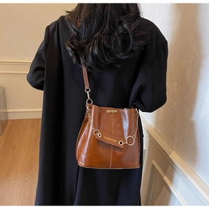 Close-up of caramel leather bucket bag with gold chain strap and fashion label detail