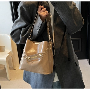 Close-up of khaki bucket bag with glossy leather texture and fashion metal chain detail