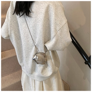 Close-up of a silver metal fish-shaped crossbody bag with detailed scale texture