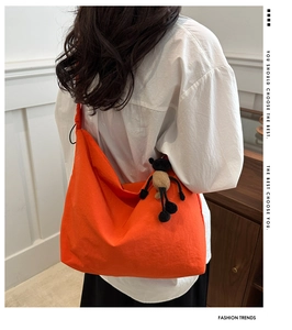 Detail of a bright orange nylon tote bag with pleated texture and plush charm
