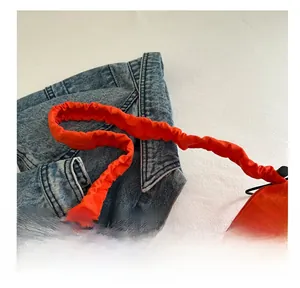Detail of the orange pleated shoulder strap on a bright nylon tote bag for women