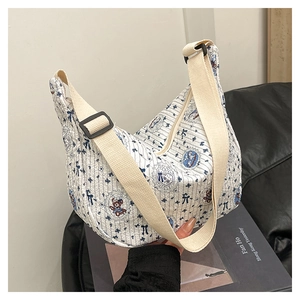 Detail of white striped canvas crescent bag featuring blue bows and cute bear illustration