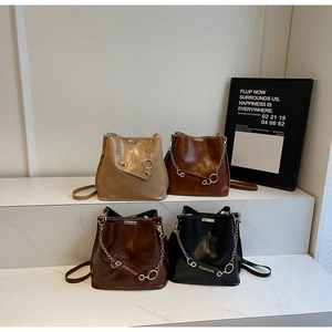 Detailed view of leather bucket bags in four colors with gold chains and fashion tags