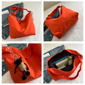 Detail view of large orange canvas tote bag with shoulder strap and plush lamb charm