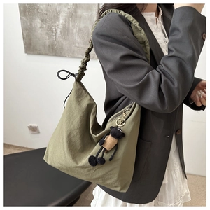 Detail of army green nylon tote bag with pleated strap and cute lamb plush pendant