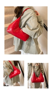 Dettagli di una borsa sottobraccio in pelle lucida rosso vivo indossata da una modella