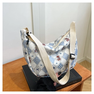 Close-up of crescent-shaped quilted bag with teddy bear print and wide strap