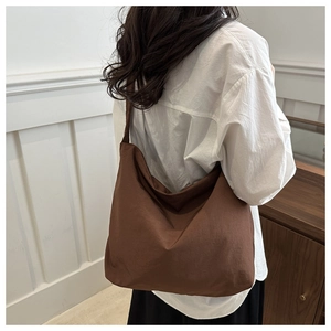 Rear view of a large brown canvas tote bag worn by a model for a size comparison