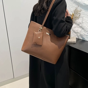 Brown lychee leather tote bag with small envelope pouch shown on model shoulder