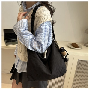 Close-up of black canvas tote bag featuring unique ruffled shoulder straps and cute lamb charm
