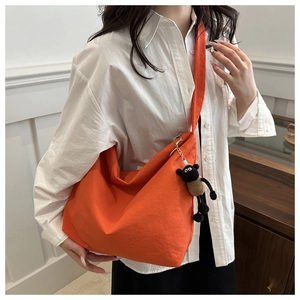 Detail of orange canvas tote bag with a cute sheep plush charm on wide shoulder strap