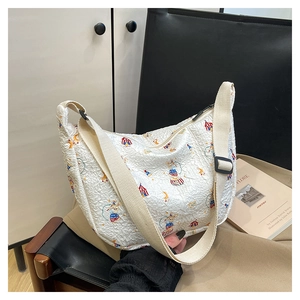 Detail of white square bag featuring textured circus prints and canvas shoulder strap