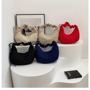 Primer plano de cinco bolsos de media luna plisados en varios colores sobre pedestales