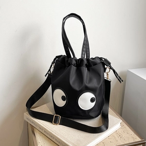 Quirky nylon bucket bag with eye patches and leather handle on a book display