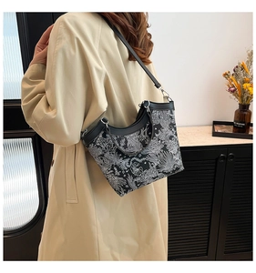 Detail of floral pattern tote bag with adjustable strap worn with a beige trench coat