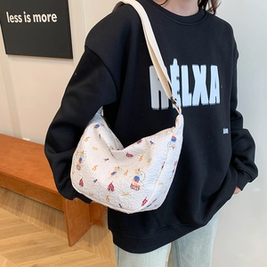White textured crossbody bag with circus cartoon prints worn by model in streetwear