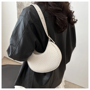 Detail of white crescent shoulder bag featuring premium faux crocodile embossed texture
