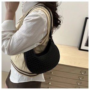 Detailed texture of black woven crescent bag with leather strap shown on a model